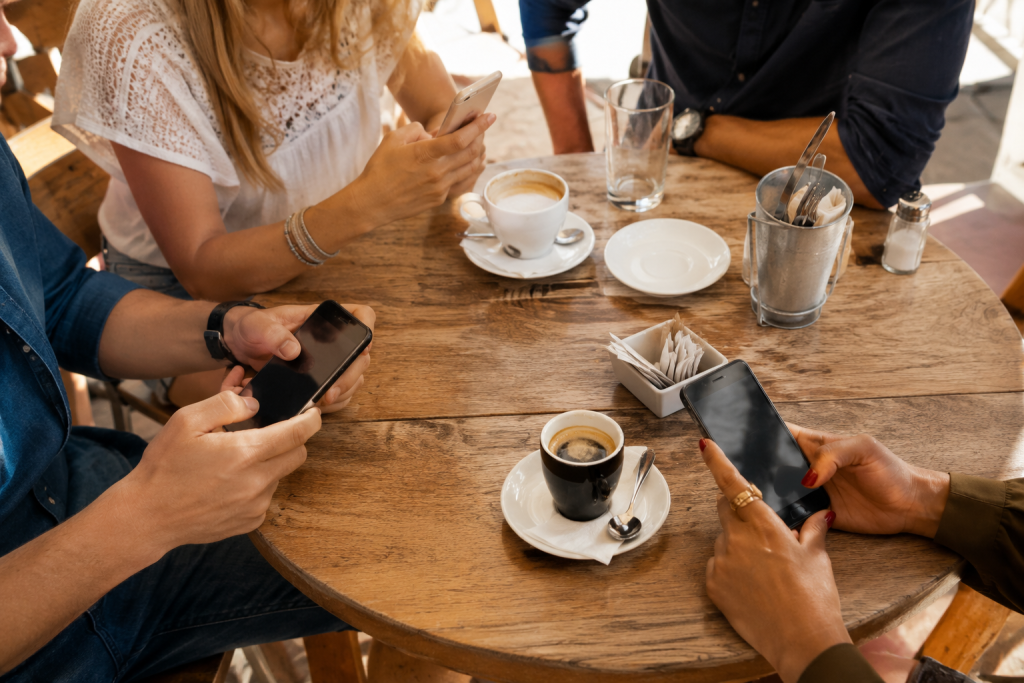 La vie bancaire en Espagne : prélèvements, cartes et différences avec la France 7 Banque en Espagne : groupe de personnes consultant leurs comptes bancaires sur smartphone autour d’un café