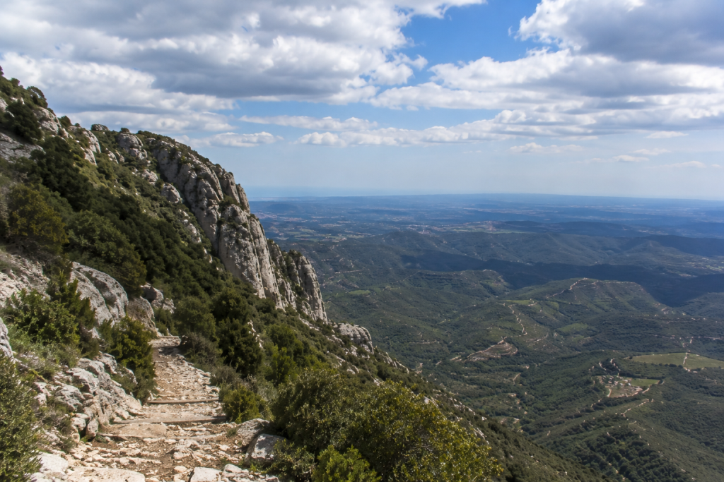 Hors des sentiers battus : les meilleures randonnées autour de Barcelone 7 Randonnées autour de Barcelone avec vue panoramique sur les montagnes et la vallée depuis un sentier rocheux.
